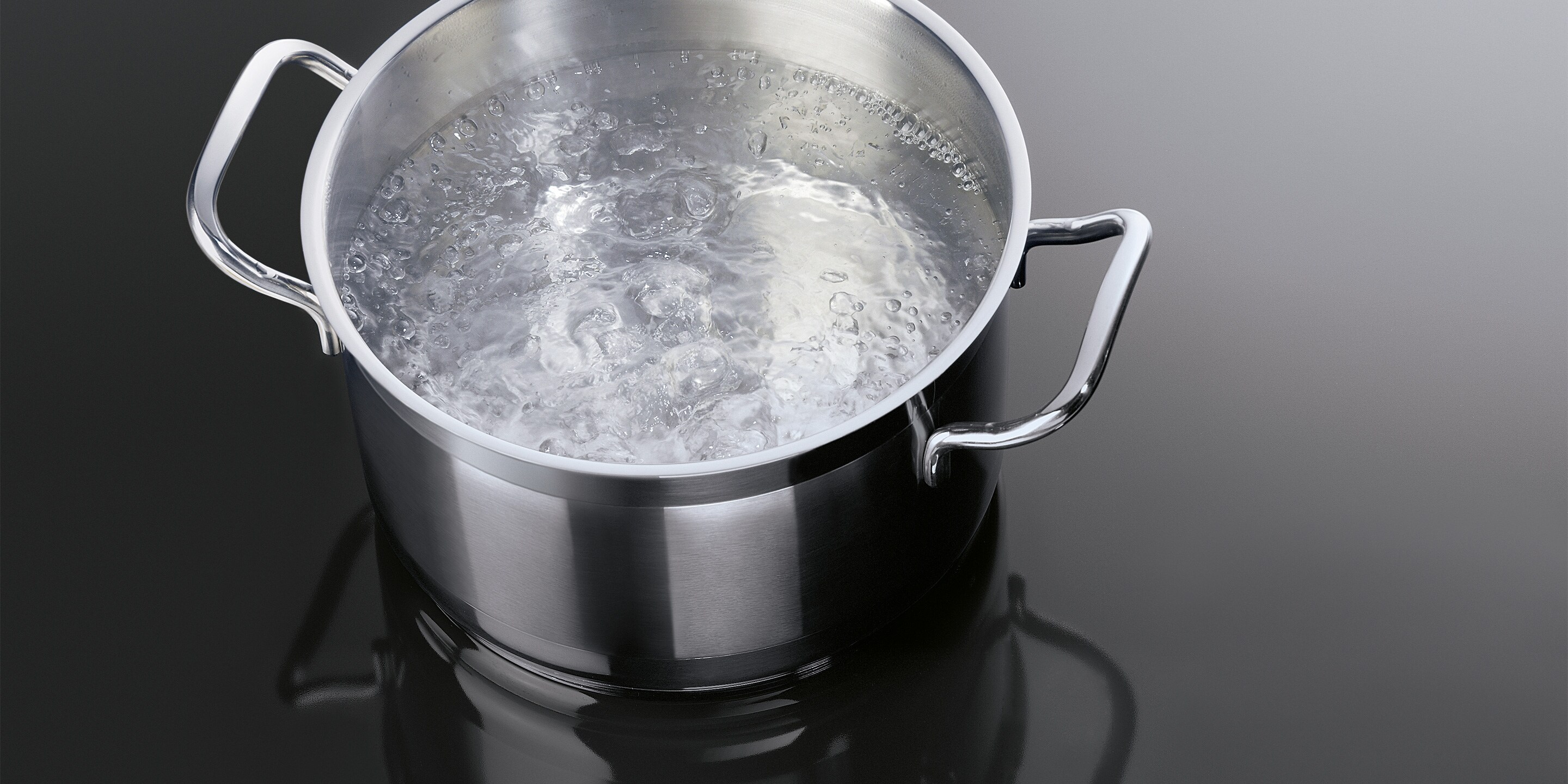 Eau en ébullition dans une casserole posée sur une table à induction AEG