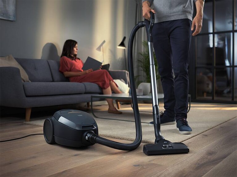 Femme qui lit pendant qu'un homme passe l'aspirateur