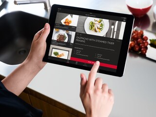 Une cuisinière passionnée consulte des recettes sur son iPad avec l’application My AEG