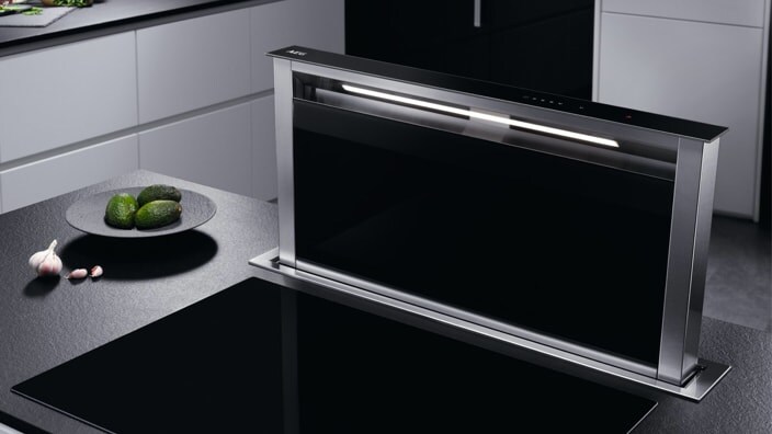 Hotte à aspiration vers le bas à côté d’une plaque de cuisson