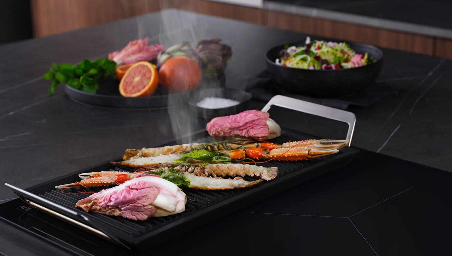 Différents types d’aliments sont préparés sur une taque de cuisson à induction dotée de la fonction bridge.