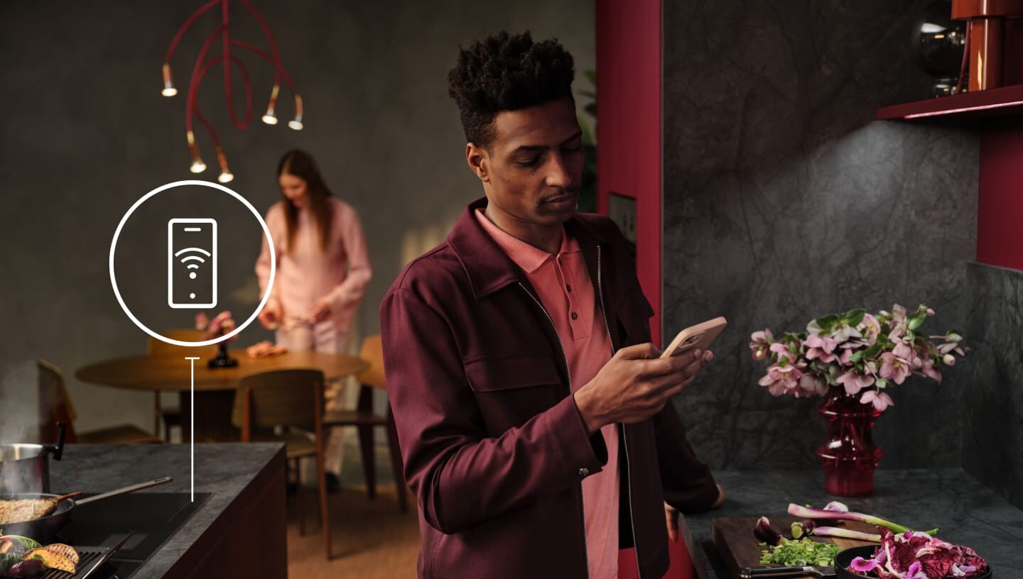 Un homme regarde son téléphone dans la cuisine.
