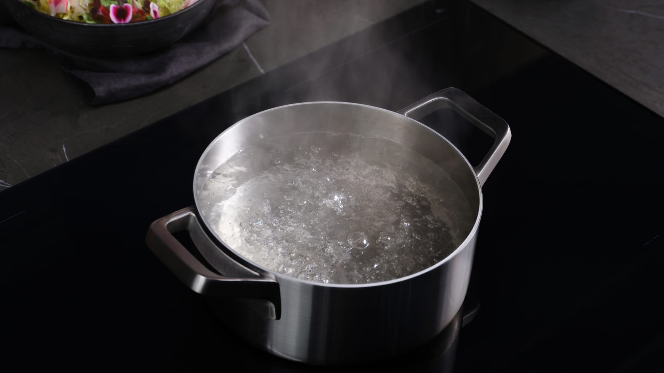 Une casserole avec de l’eau bouillante sur une taque de cuisson à induction.
