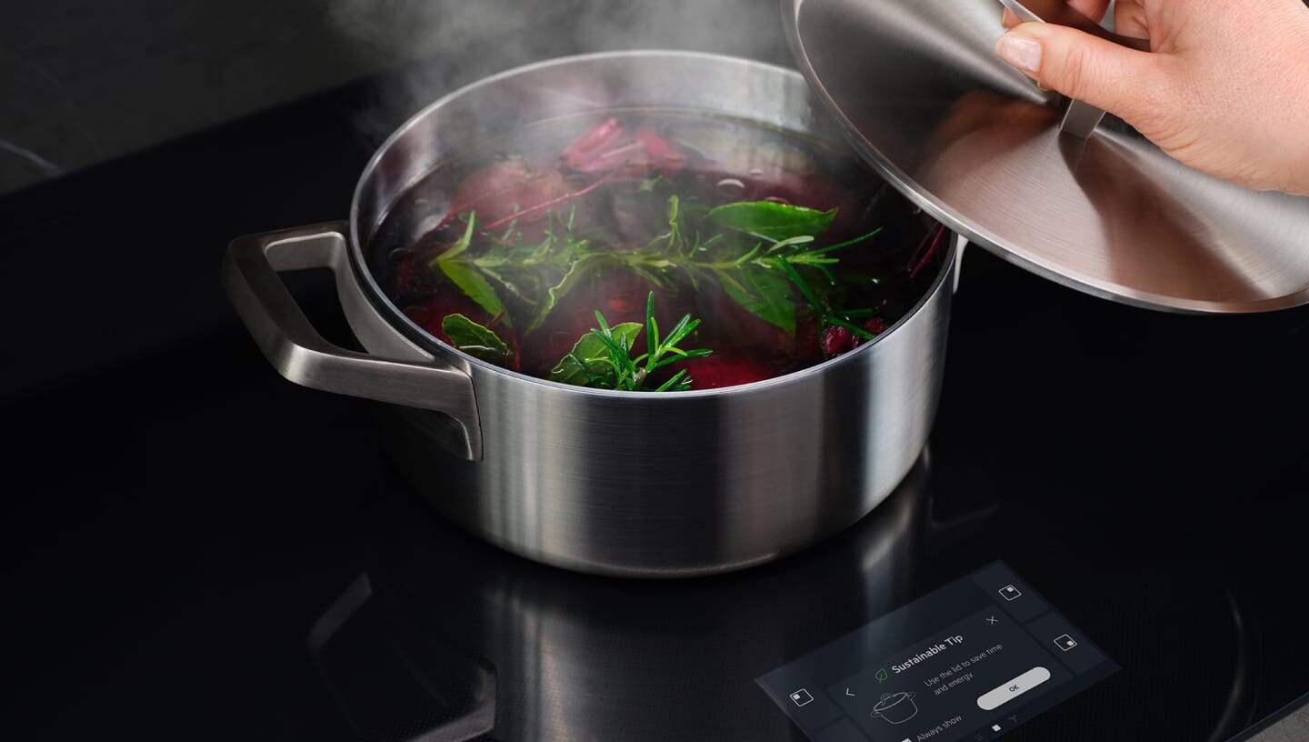 Une main retire le couvercle de la casserole de légumes bouillants.
