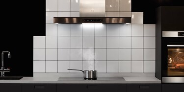 Saumon en cuisson sur une table de cuisson pendant qu’une hotte aspirante extrait les excès de vapeur