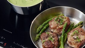 Poulet cuisant dans une poêle sur une table à induction AEG