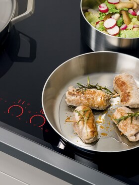 Viande en train de cuire dans une poêle Mastery Collection avec des asperges