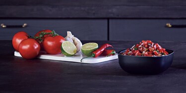 Tomates, citron vert, piment et ail sur une planche à découper