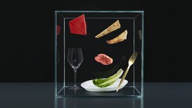 Un assortiment de couverts, assiettes et aliments dans un cube de verre pour représenter le pilier Expérience de Taking Taste Further.