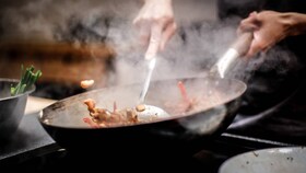 Des aliments cuisant dans un wok sur une table de cuisson à induction AEG