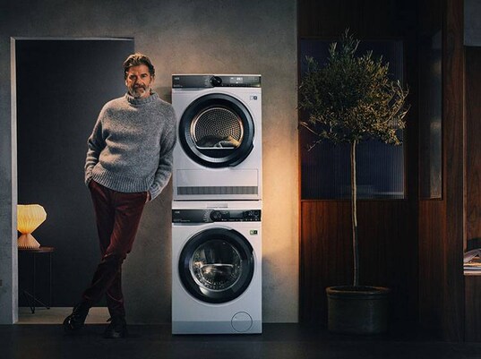 Homme à côté d'un lave-linge & sèche-linge