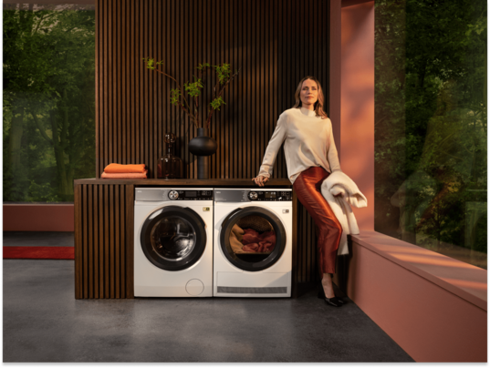 Femme debout à côté d'un lave-linge et d'un sèche-linge AEG.