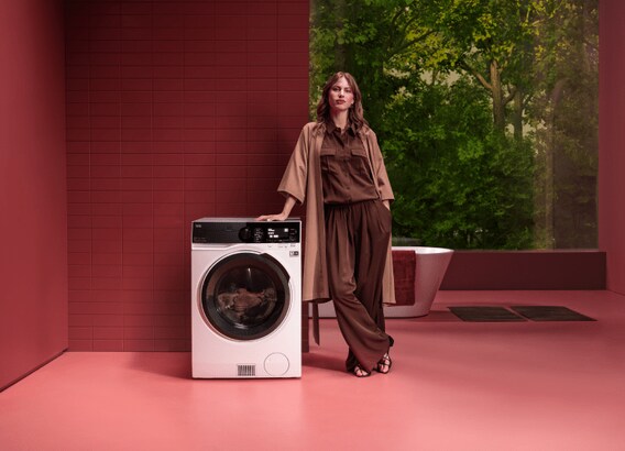 Femme debout à côté d'une machine à laver AEG.