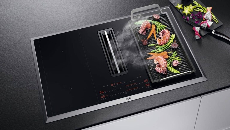 Cuisson des aliments sur une plancha placée sur une plaque de cuisson AEG.