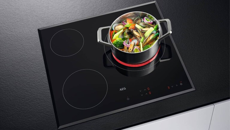 Cuisson d’aliments dans une casserole placée sur une plaque AEG.