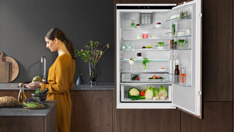 Femme debout dans une cuisine avec la porte du réfrigérateur ouverte