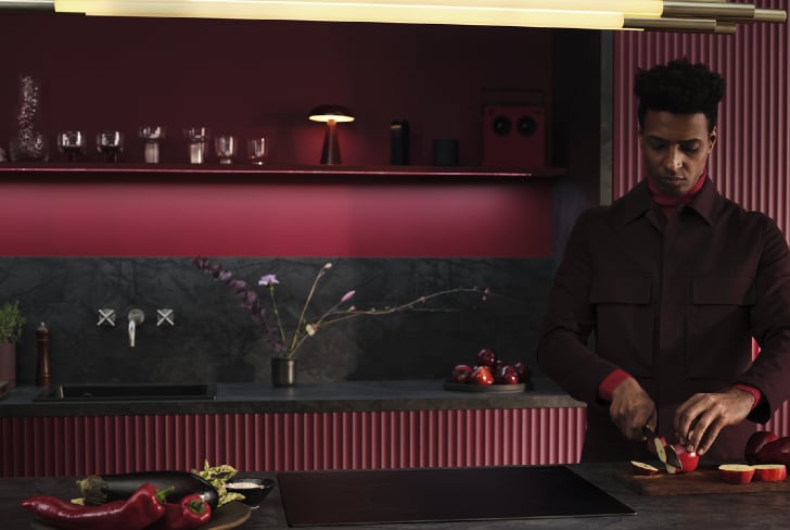 Un homme coupant des fruits dans une cuisine.