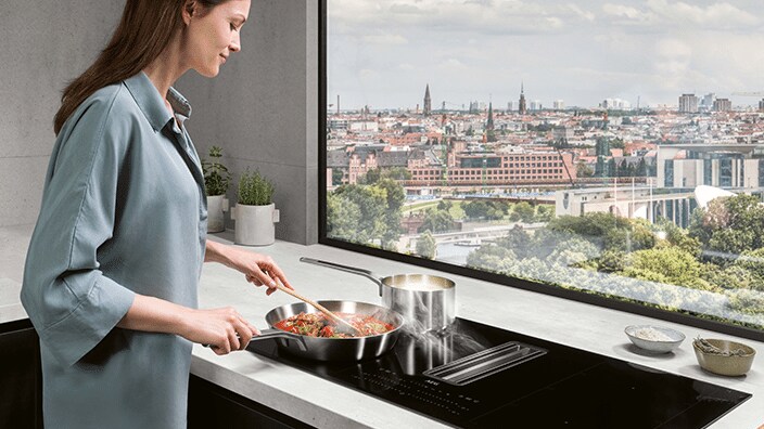 Femme cuisine devant une fenêtre