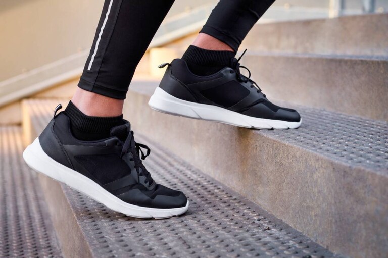 Des chaussures et des jambes visibles d'une personne montant un escalier.